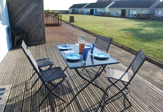 Enjoy breakfast on the decking with views across the communal lawn towards the sea.