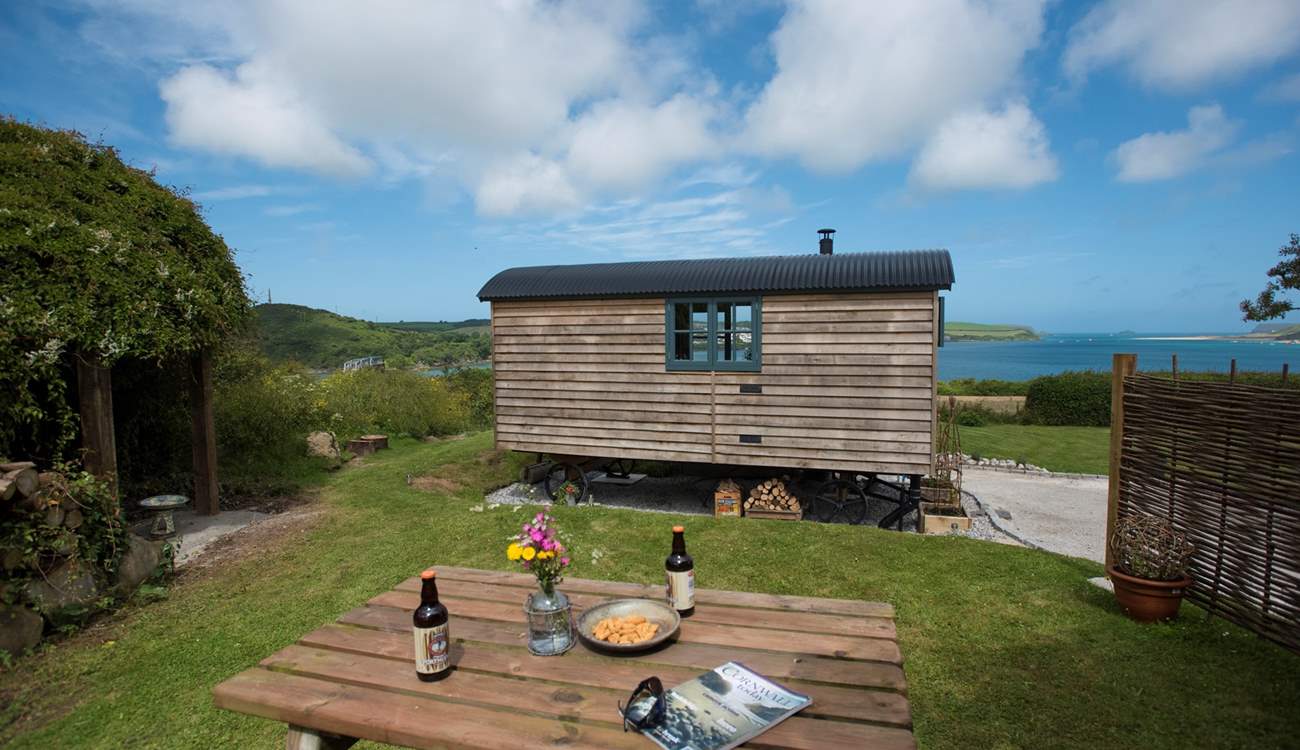 The picnic table is behind the hut, in the screened off garden area.