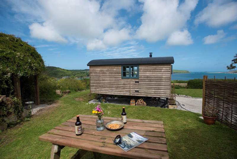 The picnic table is behind the hut, in the screened off garden area.