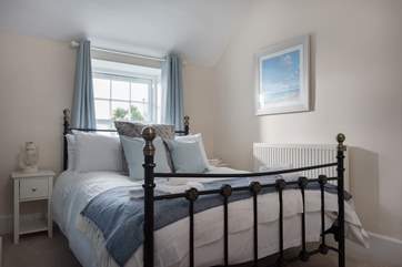 Bedroom 1 with a metal double bed and views over the garden.