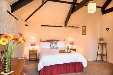 The bedroom retains much of the character of the original barn, with stone walls and exposed beams.