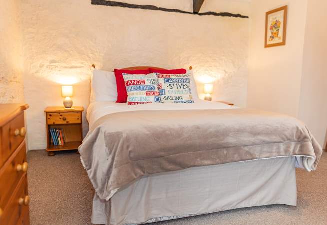 The bedroom retains much of the character of the original barn, with stone walls and exposed beams.