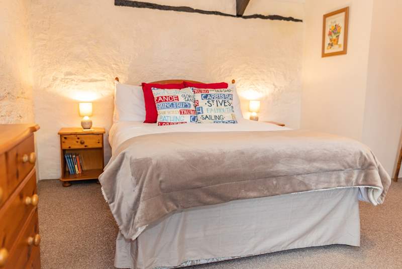The bedroom retains much of the character of the original barn, with stone walls and exposed beams.