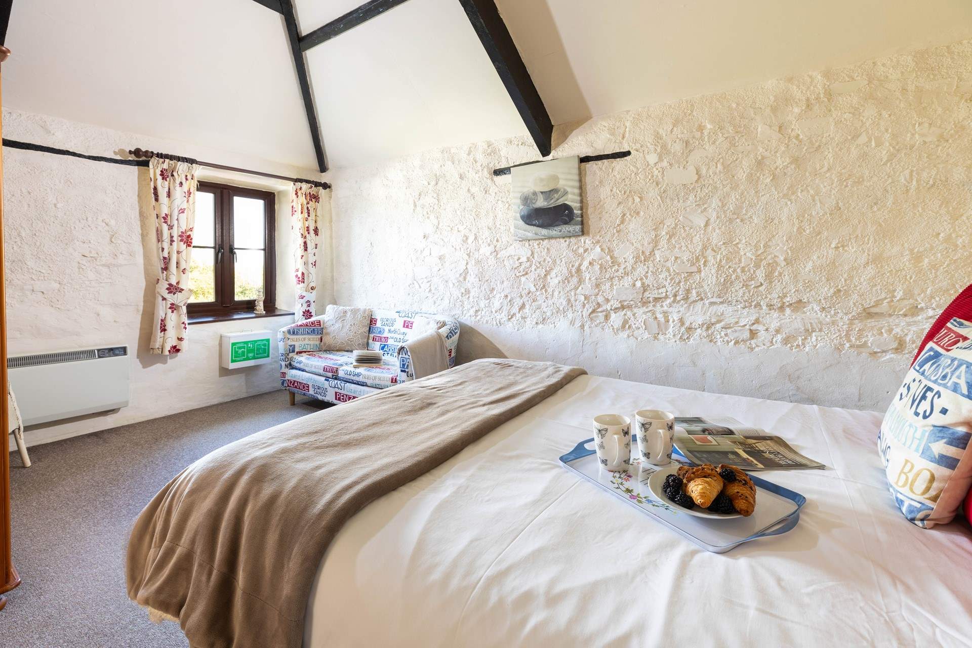 The bedroom retains much of the character of the original barn, with stone walls and exposed beams.