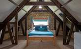 The master bedroom has sloping ceilings with revealed beams, feature stonework and dressing-area. - Thumbnail Image