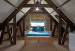 The master bedroom has sloping ceilings with revealed beams, feature stonework and dressing-area.