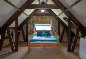 The master bedroom has sloping ceilings with revealed beams, feature stonework and dressing-area.