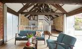 The open plan living area with exposed beams and high ceiling.  The patio sliding door leading on to the outdoor courtyard with al fresco dining area. - Thumbnail Image