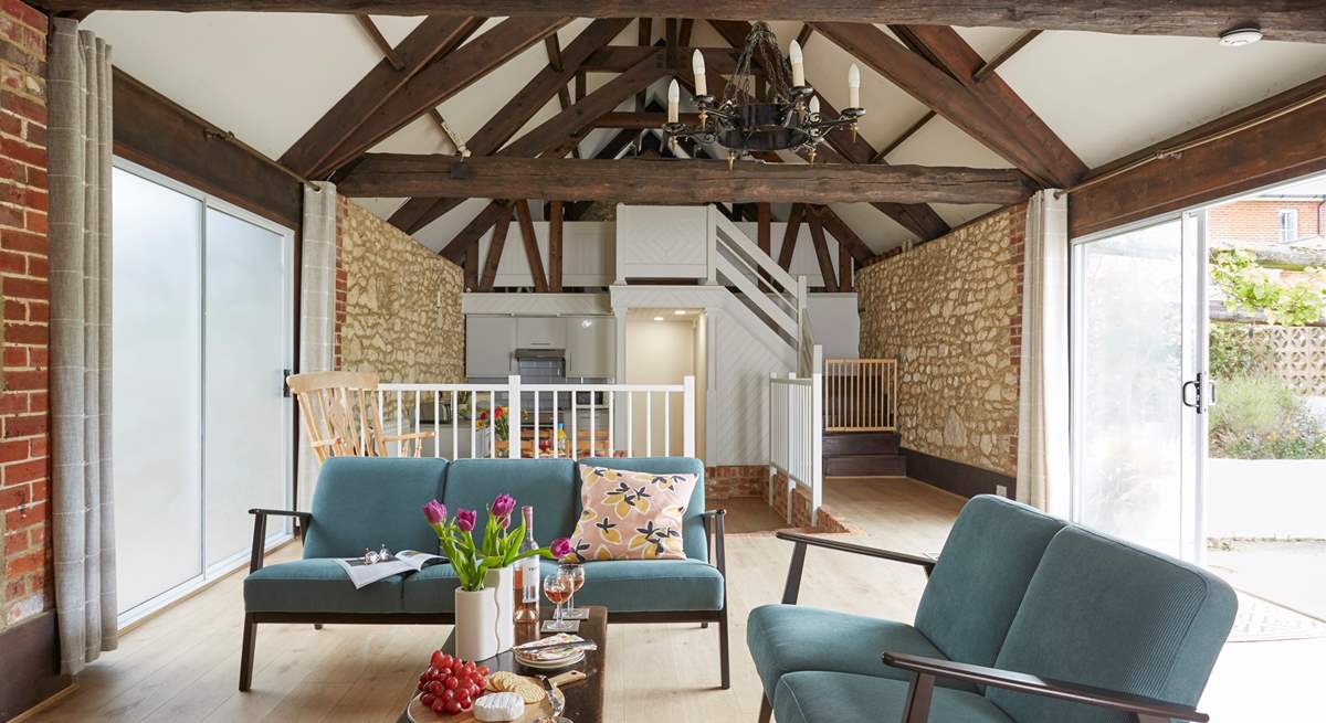 The open plan living area with exposed beams and high ceiling.  The patio sliding door leading on to the outdoor courtyard with al fresco dining area.