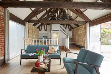 The open plan living area with exposed beams and high ceiling. The patio sliding door leading on to the outdoor courtyard with al fresco dining area.