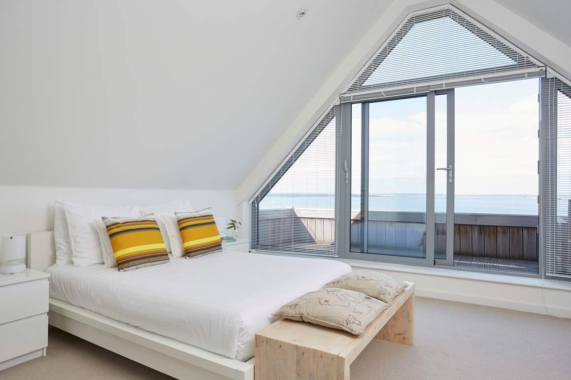 Bedroom 5 has doors opening out to the balcony, with seating to enjoy the fabulous view.