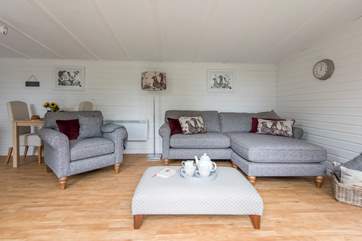 The comfortable L-shaped sofa set in the corner looking out to the decked patio area and trees beyond.