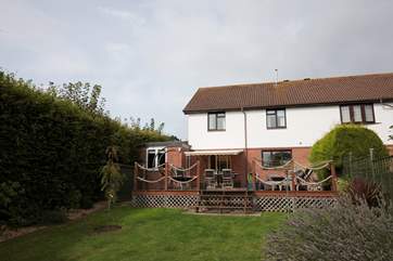 The rear of the house, with lawned area and steps up to the decked area.