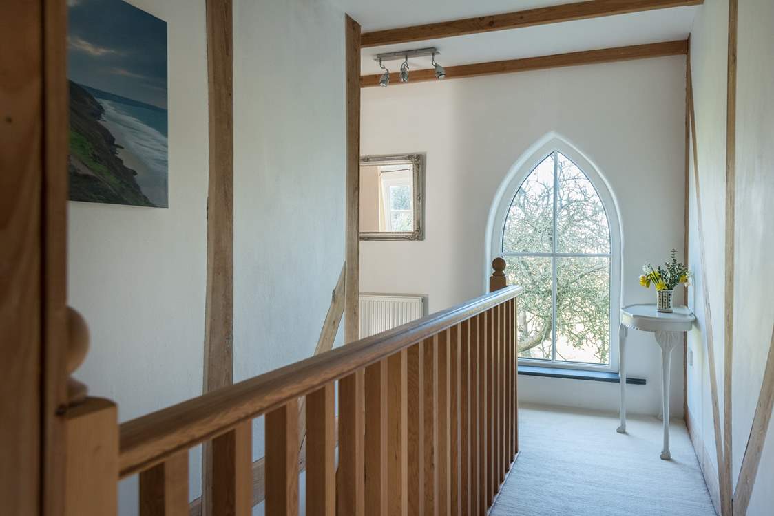 The landing with the main bedroom on the left, and views through the beautiful feature window over the countryside beyond.