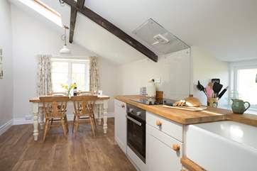 The contemporary kitchen is fully-equipped and the dining table looks out over the side garden.