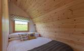 The cosy double bed is set at the rear of the pod with a window looking out to the meadow at the back. - Thumbnail Image