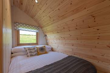 The cosy double bed is set at the rear of the pod with a window looking out to the meadow at the back.