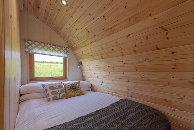 The cosy double bed is set at the rear of the pod with a window looking out to the meadow at the back.