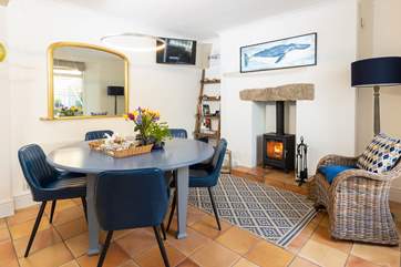 The dining area has comfy chairs, enjoy sitting around the table with the cosy wood burner glowing.