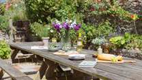 The patio off the kitchen is home to a huge outdoor dining area and surrounded by stunning colour and greenery.