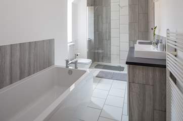 The stylish family bathroom has a double shower and very large bath.