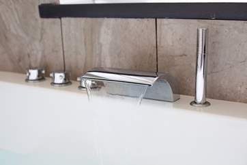 The contemporary bathroom has a jacuzzi bath...