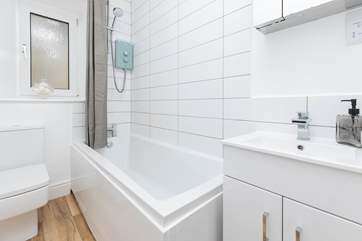 The bathroom has a shower over the bath.