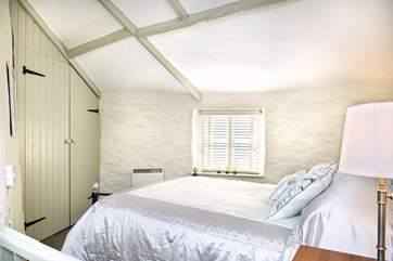 The bedroom is painted in soft Farrow and Ball shades. The vaulted ceiling gives the room a sense of space.