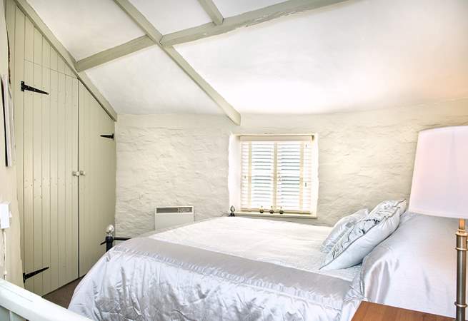 The bedroom is painted in soft Farrow and Ball shades. The vaulted ceiling gives the room a sense of space.