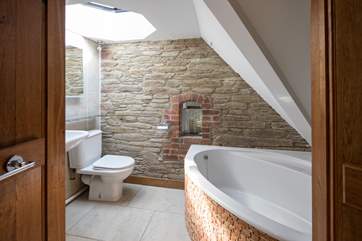 En suite to bedroom 3 boasts this beautiful corner bath and eye-catching brickwork.