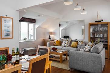 The open plan living-area has sunlight flooding in, you can see glimpses of sea views towards Porth Beach to the side, from the sitting-room.