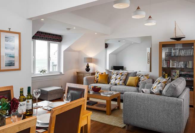 The open plan living-area has sunlight flooding in, you can see glimpses of sea views towards Porth Beach to the side, from the sitting-room.