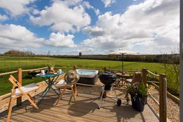 The raised deck overlooks the pretty patio-area and the huge meadow beyond.