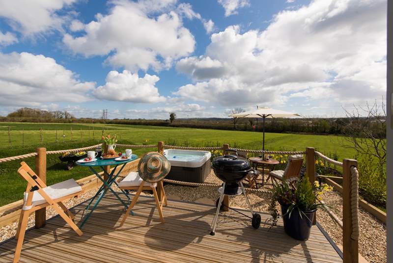The raised deck overlooks the pretty patio-area and the huge meadow beyond.