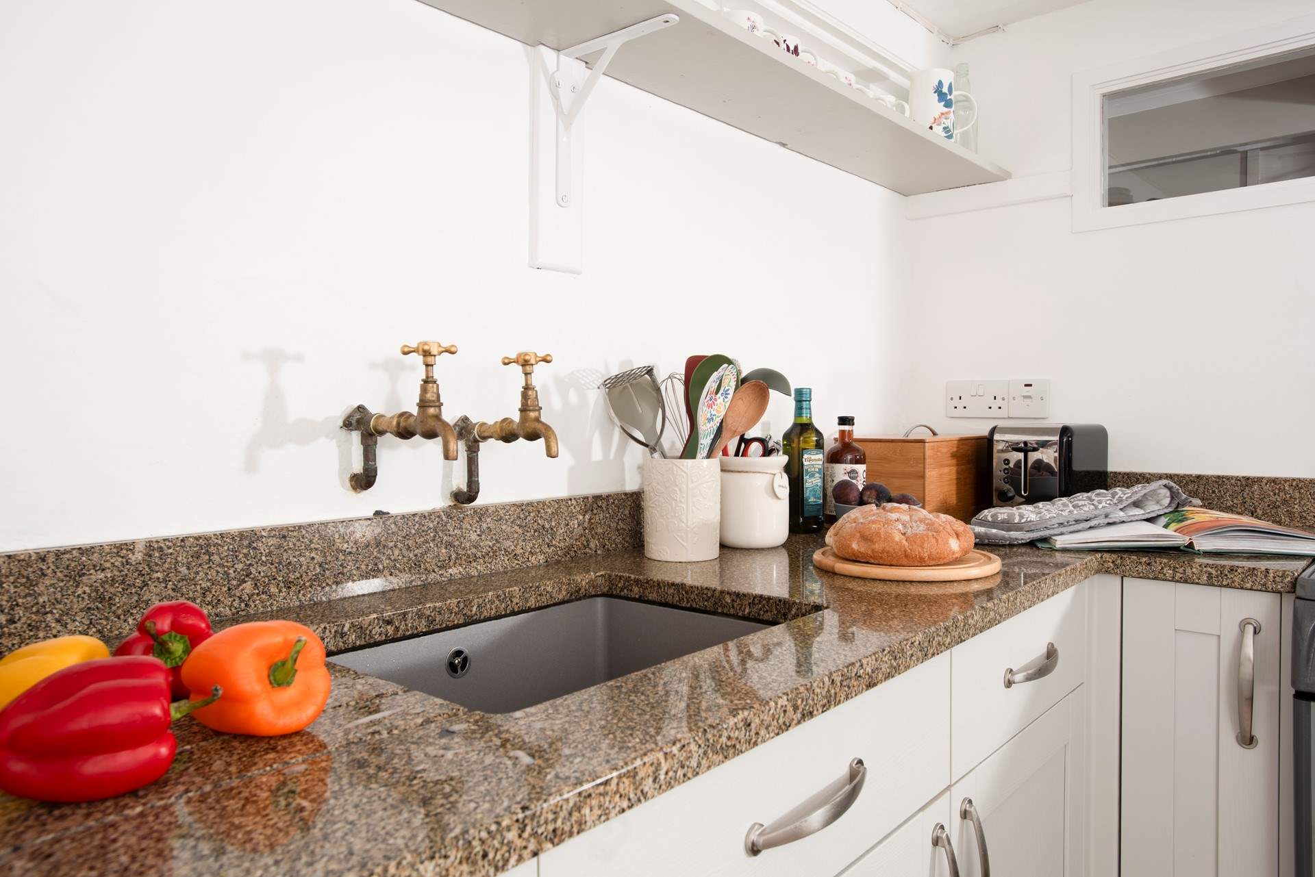 and features beautiful fixtures like these brass taps and granite workspace.