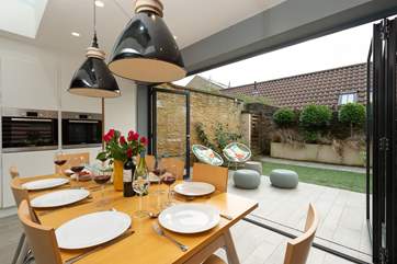 The bi-fold glass wall folds easily back so that the enclosed garden becomes part of the fabulous living space.