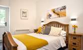 Crisp white linen and lovely cushions and throw in shades of mustard and grey, on the bed. - Thumbnail Image