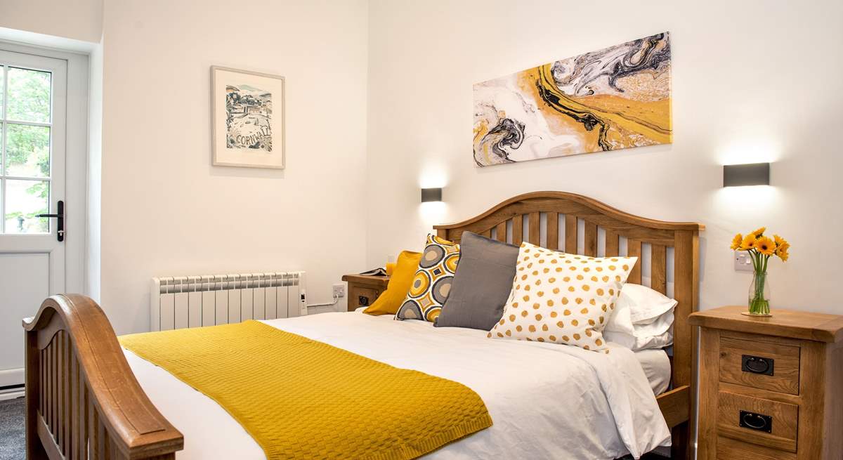 Crisp white linen and lovely cushions and throw in shades of mustard and grey, on the bed.