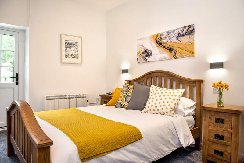 Crisp white linen and lovely cushions and throw in shades of mustard and grey, on the bed.