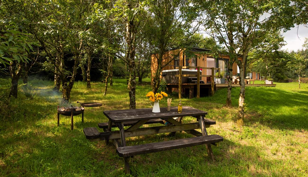 With a picnic table set under the trees, a firepit, hot tub and sun loungers, this is such a special setting.