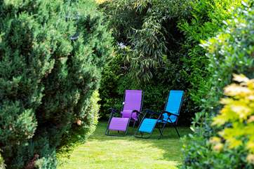 The garden extends behind the big fir trees.
