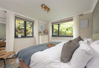 Bedroom 2 is a sleek space embraced by lush garden banks.