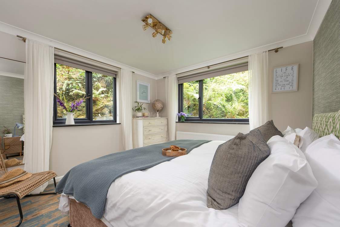Bedroom 2 is a sleek space embraced by lush garden banks.