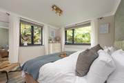 Bedroom 2 is a sleek space embraced by lush garden banks.