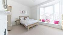 The light-filled main bedroom has a wide bay window with seating.