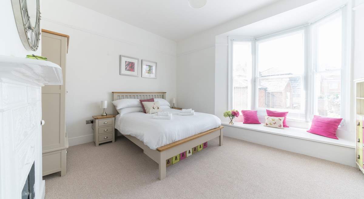 The light-filled main bedroom has a wide bay window with seating.