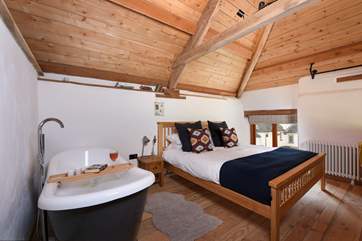 The bedroom is on a mezzanine level and boasts a gorgeous roll-top bath.