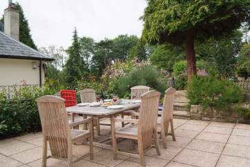 The stone terrace has beautifully planted borders and French windows from the living-area, lead straight out onto it. You can see the corner of the owner's home next door - The Coach House is on a higher level and tucked behind it.