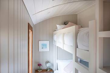 The bunk beds sit above the double bed, one either side with a partition in between.
