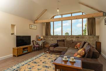 The L-shaped sofa is deep and comfortable and the large windows at the end of this open space include a glimpse of Glastonbury Tor.